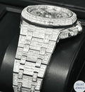 Exquisite silver watch with emerald bezel and bust-down design, adorned with sparkling diamonds for a bold look.